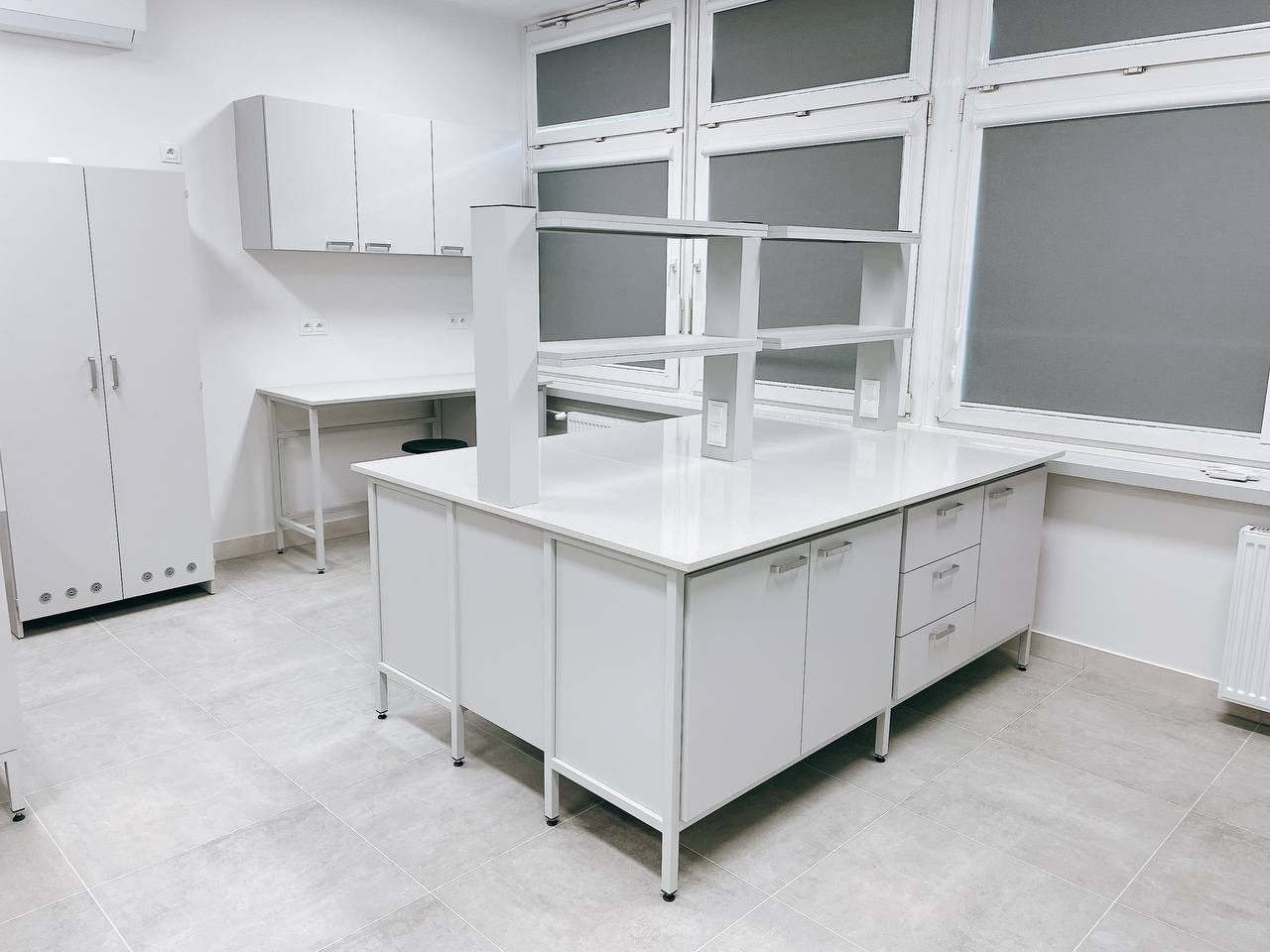 Na zdjęciu widoczny jest stół wyspowy laboratoryjny z nadstawką laboratoryjną